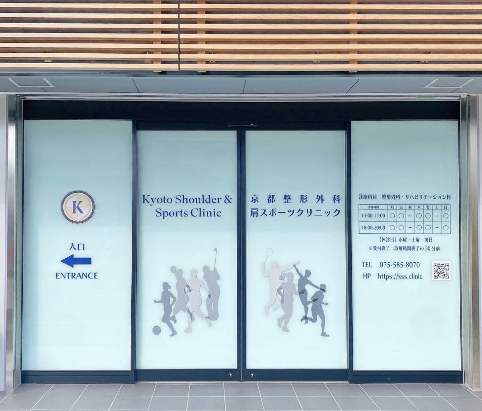 京都整形外科肩スポーツクリニックのエントランス。ガラス面にロゴと診療時間、競技者のシルエット